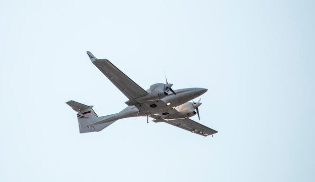 Small twin-engine propeller military reconnaissance aircraft on a background of sky.