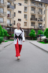 business woman in red pants, white blouse and jacket walking by the street