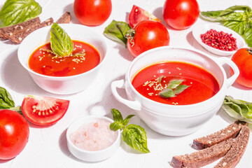 Bowls with homemade tomato soup. Ripe vegetables, fresh basil leaves, breadsticks, aromatic spices