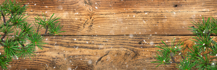 Naklejka premium Pine or fir branches on a wooden background. Christmas background with coniferous branches and snow.
