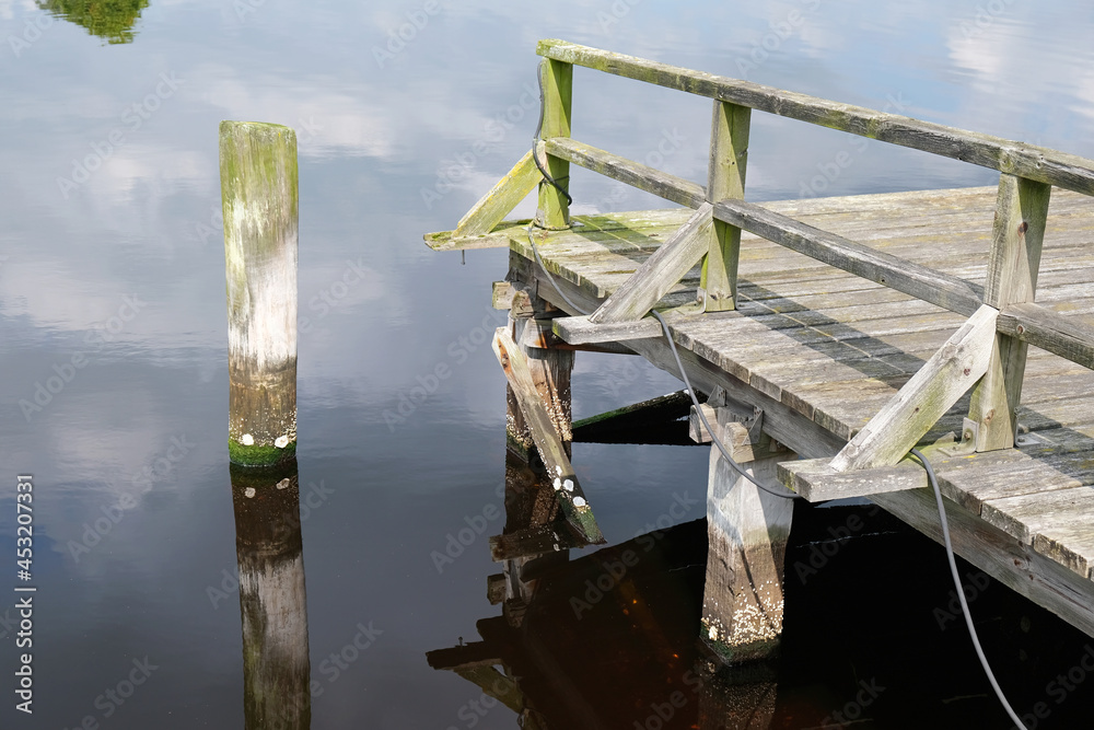 Poster Wooden boat dock surrounded by smooth water at the touristic North Sea shore