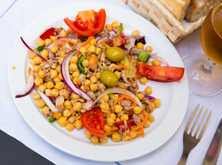 Appetizing salad with chickpeas, crumbled fish and vegetables. Traditional Spanish food