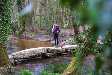 Fototapeta premium Pilgrim Girl Hiking on a Stone Bridge in Galicia Spain along the Way of St James Camino de Santiago Pilgrimage Trail