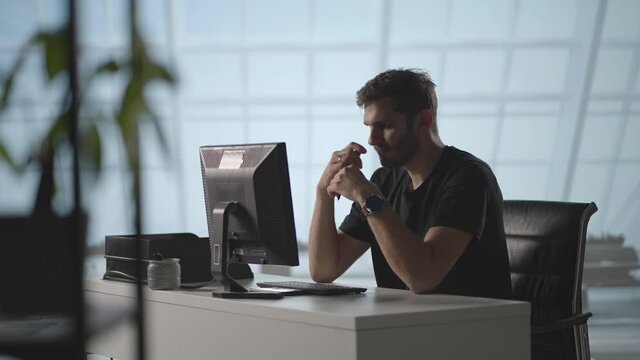A serious man sits at a computer in the office and thinks. Analyzes solves a crisis problem. A difficult stage in business. Thoughtful businessman