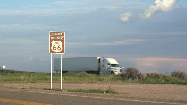 Semi trucks pass by on an interstate highway next to old Route 66