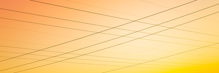 Power lines in the warm sky background at sunset. Abstract geometry of lines and harmony of yellow and orange colors.