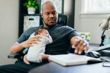 Black dad with newborn working from home
