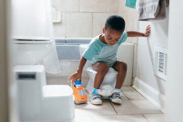 Black boy, potty training time at home, playing with toy truck