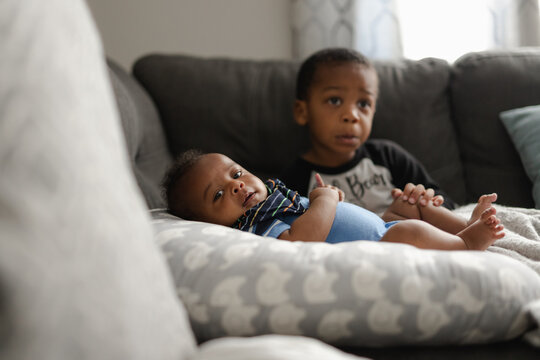 Black boys, siblings, sitting and laying on sofa