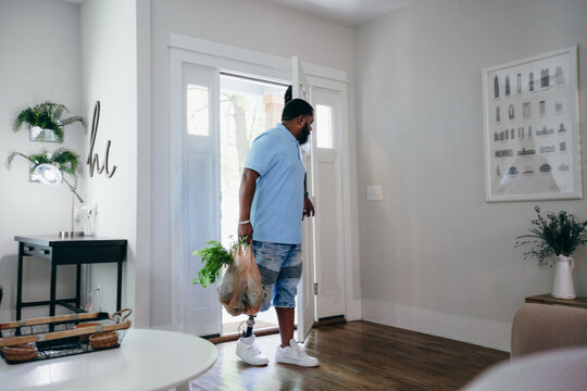 Black man with prosthetic leg bringing home groceries
