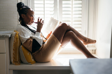 Self Care - black woman relaxing, reading book, and drinking wine