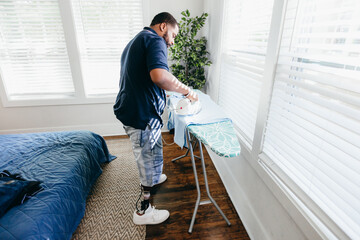 Black man ironing clothes, everyday life, disabled