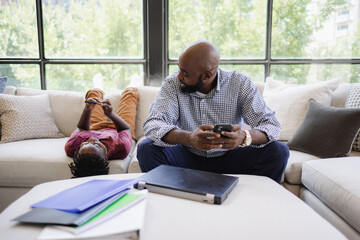 Father and son using smart phones on sofa