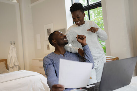 Smiling African American couple holding document and fist bumping