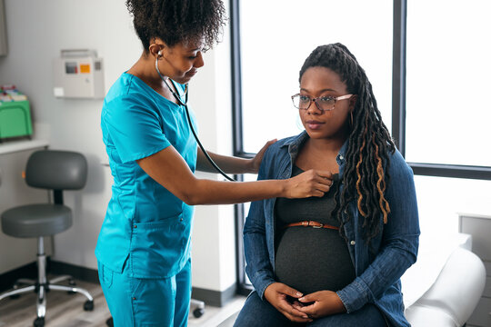 Black woman nurse checks vitals of pregnant patient