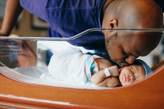 Black dad kisses newborn at hospital