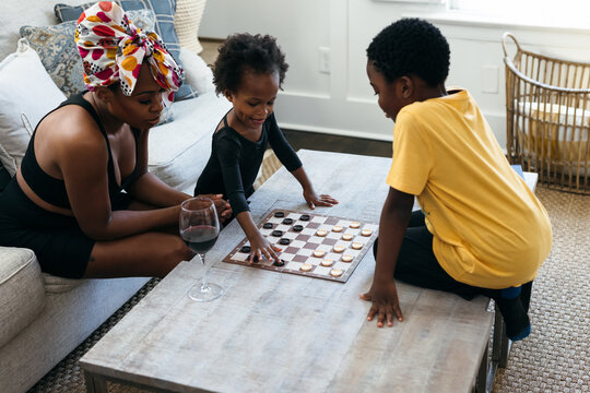 African American family playing checkers game at home