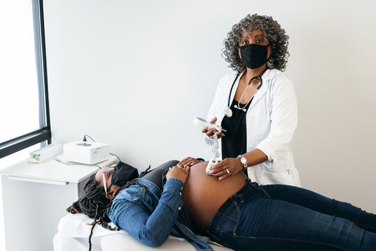 Female senior doctor listening to heartbeat, looking at camera, using a doppler sonogram