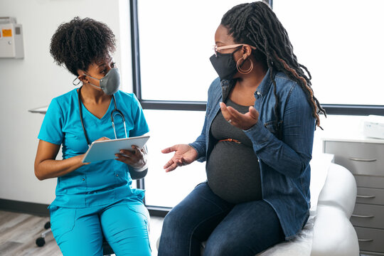 Nurse speaks with patient in medical exam room