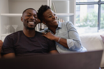 Black Couple sitting on sofa and laughing