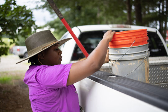 Female Farmer Loading Buckets Into Pick Up Truck