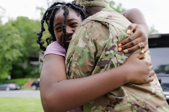 Black military man embraces daughter as he is welcomed home
