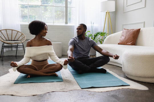 Young Black couple meditating in living room, wellness 