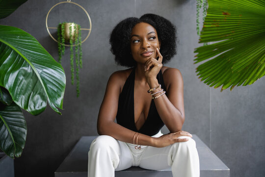 Elegant Young Woman Sitting Among Plants