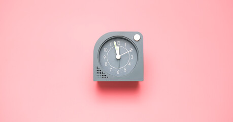 Alarm clock isolated Showtime 11.57 am or pm on pink background.