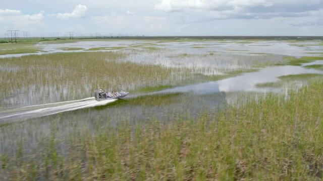Aerial view around a hovercraft, driving in middle of swamps of Everglades, Miami - orbit, drone shot