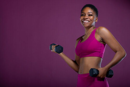 Smiling Black woman workout with dumbbells and copy-space