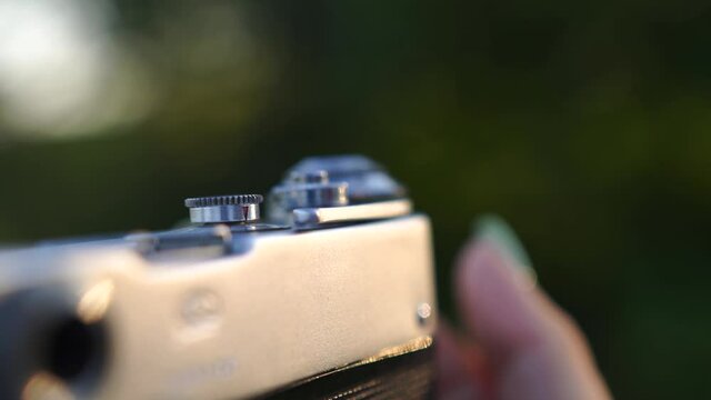 close-up female hand adjusts retro camera, exhibits focus, light and other settings, checks camera shutter, prepares for shooting, photo shoot, video shooting, controls camera capture beautiful frame