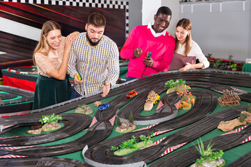 Girls with guys play together a slot car racing models