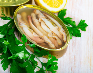 Marinated in oil Navajas shellfish served in tin with lemon and greens