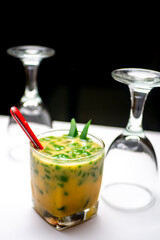 Ice Cendol with red spoon decoration with empty glasses as background photographed on white table