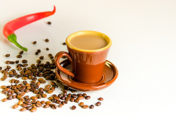 Old rare Scandinavian cup brown color of baked clay with coffee and milk in a saucer placed on a table on which coffee beans are scattered Arabica and hot chili peppers