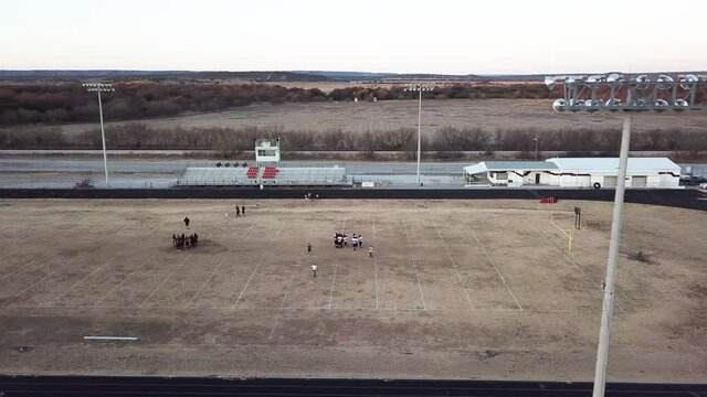 Drone footage of Texas high school football field during practice behind stadium lights