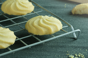 Close up image homemade butter cookies put on wire rack with wooden tray on the table.