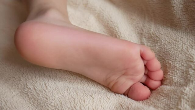A child puts the foot on a soft blanket close-up
