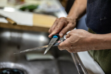 man's hand sharpening the knife in the kitchen