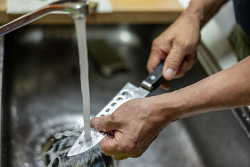 Man's hand washing the knife with water
