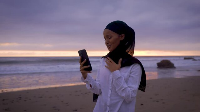 Somali-American woman checking her social media at a beach in Malibut.
