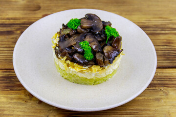 Tasty layered salad with roasted mushrooms, potato, eggs, cheese and mayonnaise on wooden table