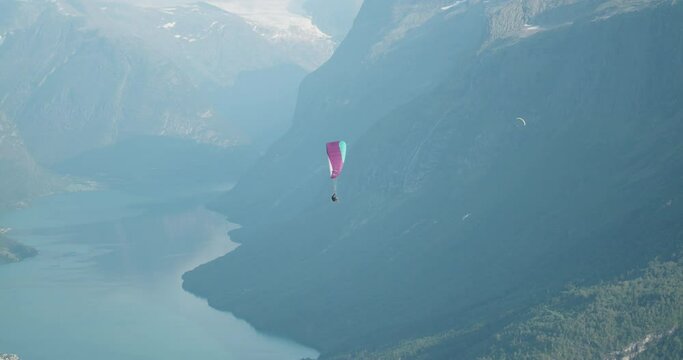 Paraglider flying above mountains and blue fjord landscape in west Norway