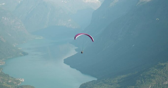 Paragliders flying high above blue narrow fjord and mountains in west Norway