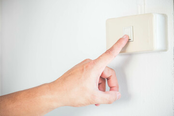 Close up of finger is turning on or off on light switch. energy saving and environmental...