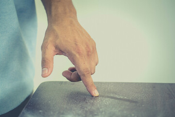 Close-up of dust on man finger taken from wooden table