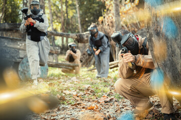 Fototapeta premium Men and women in protective uniform playing paintball on shooting range