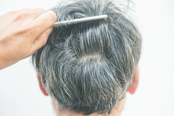 The old man opened the gray hair roots with a comb. Gray hair problem concept