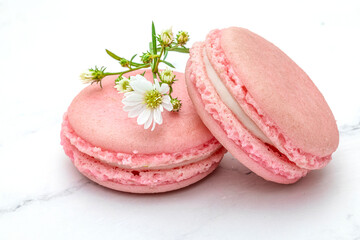 Close up of two pink macaroons or French macarons on a white marble top background.